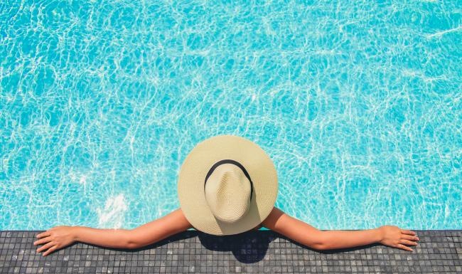 a person lying in a pool with a hat on