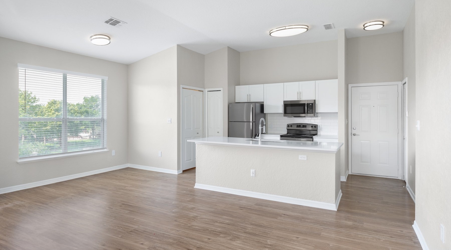 a kitchen with white cabinets and wood floors