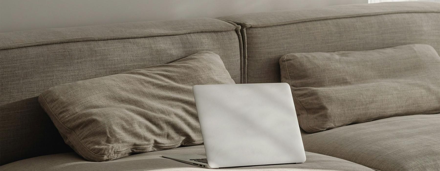 a couch with pillows and a laptop